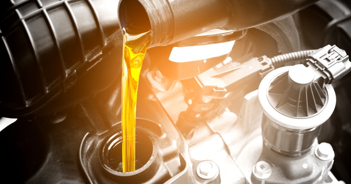 Fresh engine oil being poured into a diesel truck engine during an oil change.