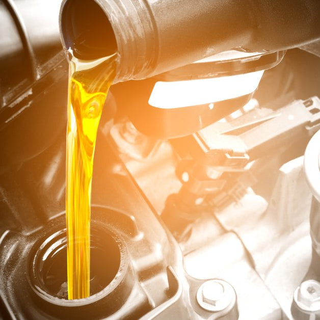 Fresh engine oil being poured into a diesel truck engine during an oil change.