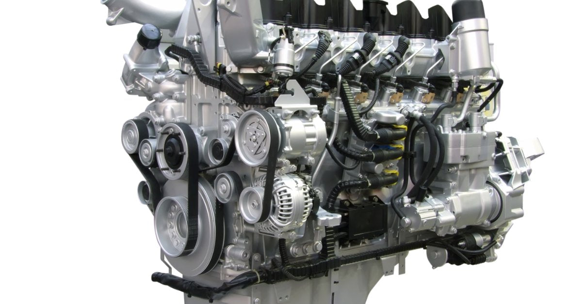 A modern diesel engine assembly on a white background, with exposed belts, pulleys, injectors, and wiring harnesses.